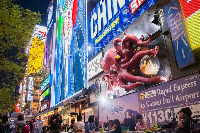 오사카 도톤보리의 네온 간판과 문어 모양 간판 아래 걷는 사람들